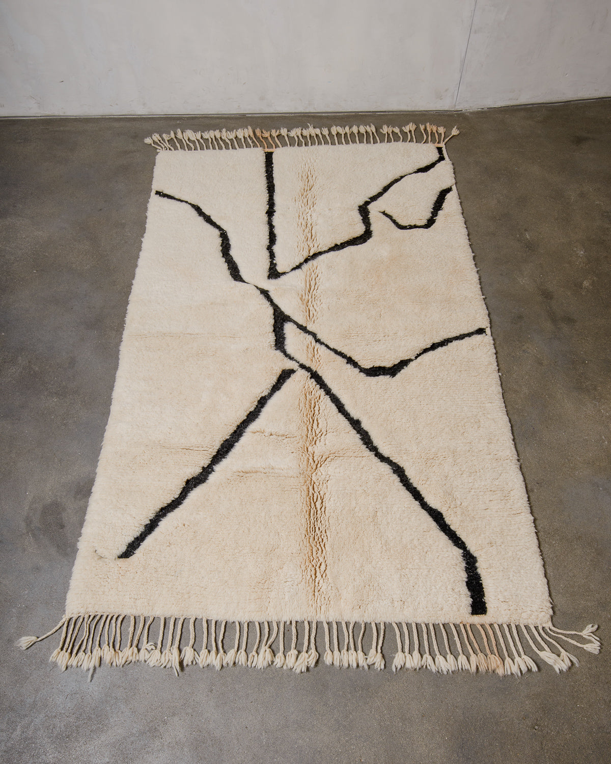 Beige and black geometric rug on a concrete floor